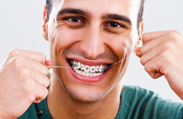 The young man is flossing his braces with smiling