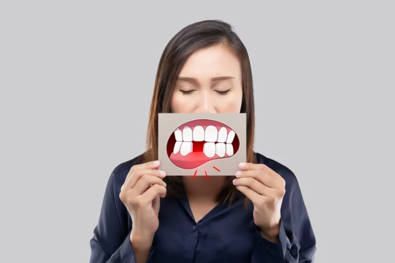 Woman holding a missing tooth image in front of her mouth