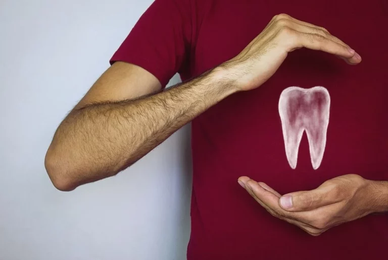 a man is holding a white tooth icon as symbol of insurance